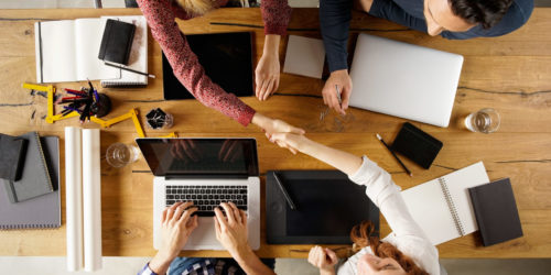 Top view of businesspeople shaking hands after sealing a deal. High angle view of casual businesswomen shaking hands after concluding business agreement.